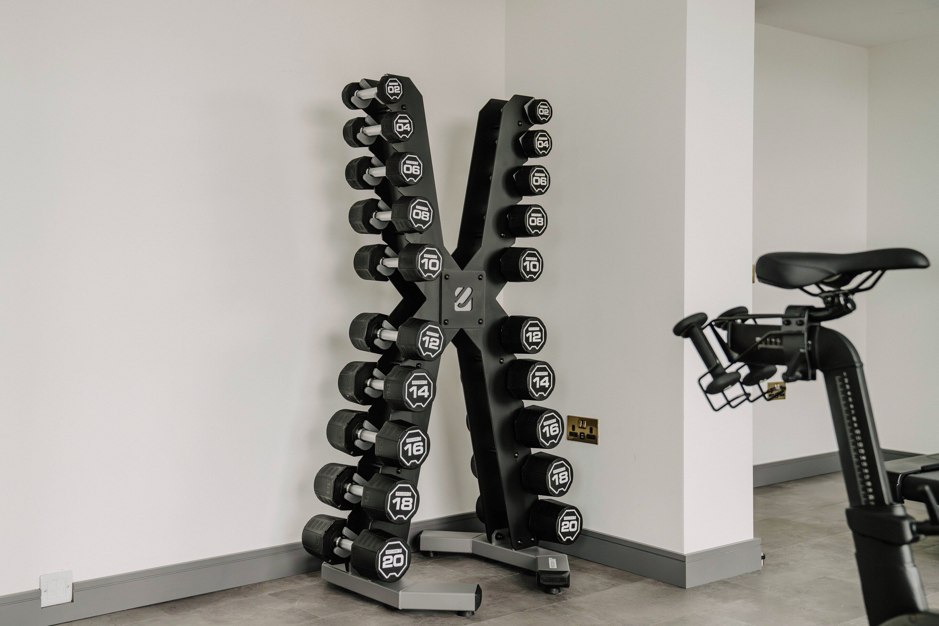 Un gimnasio en casa con un soporte de mancuernas en la pared y una bicicleta estática.