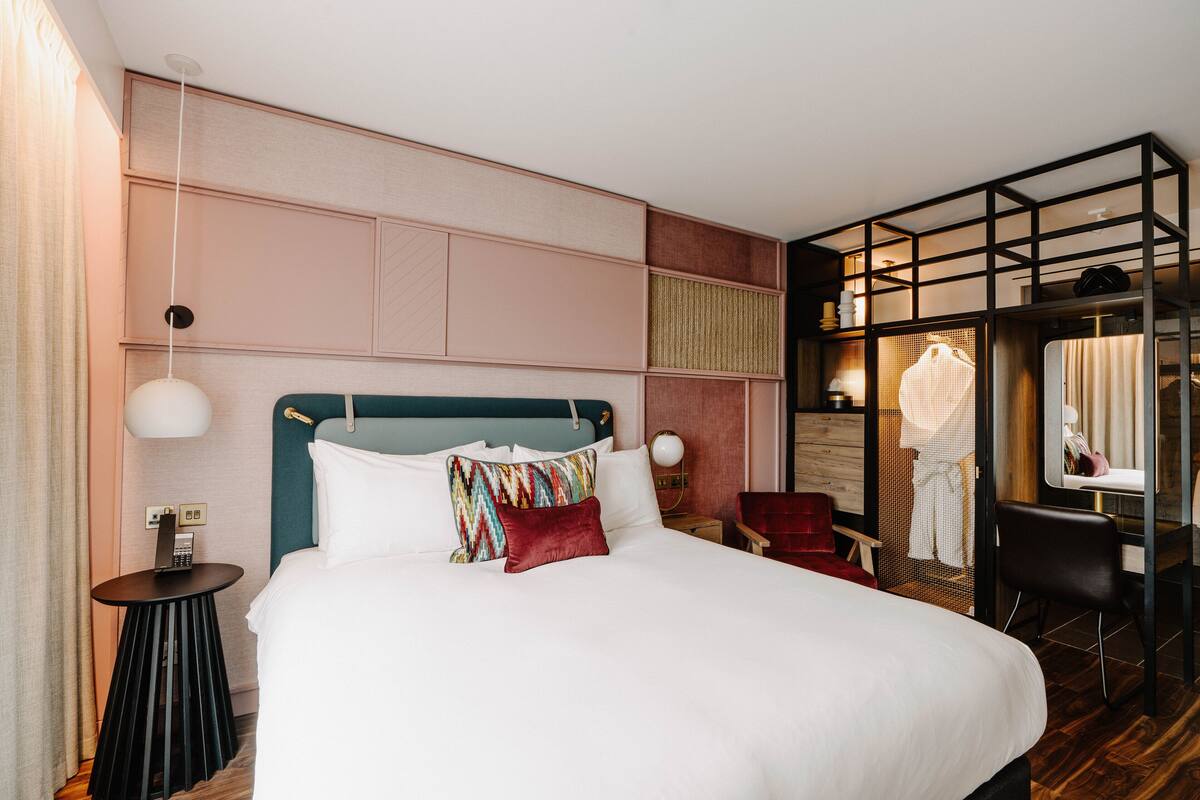 A modern hotel room with a large bed, a desk, and a seating area.