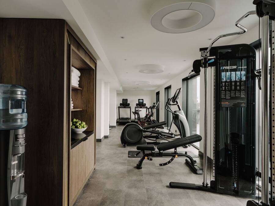 A modern gym with exercise equipment, a water dispenser, and a treadmill.
