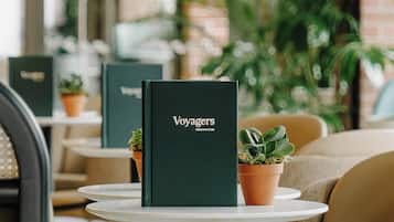 A menu stand with the word "Voyagers" on it, placed on a white table in a cafe setting.