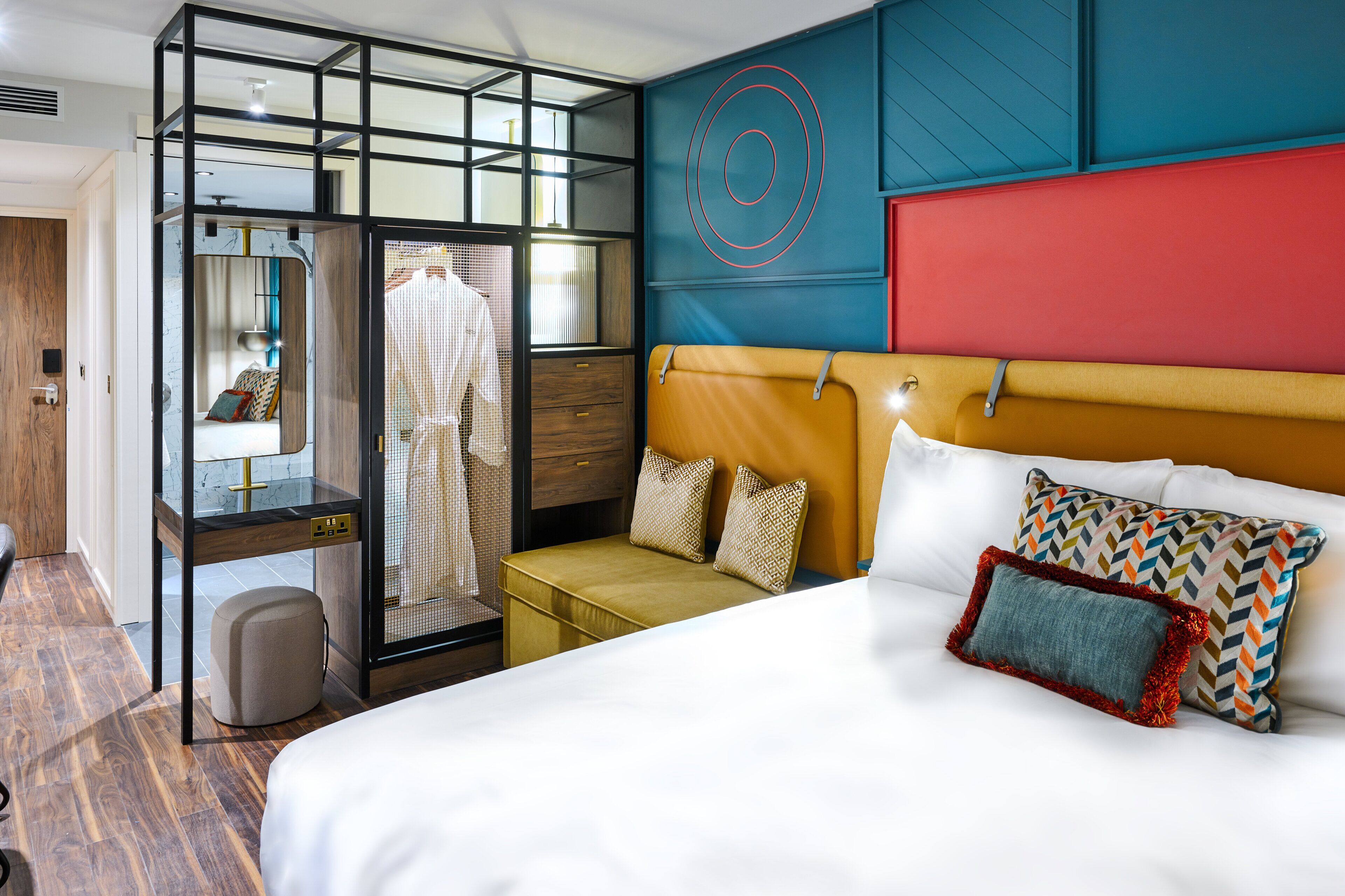 Een hotelkamer met een bed, zithoek, garderobe en spiegel.