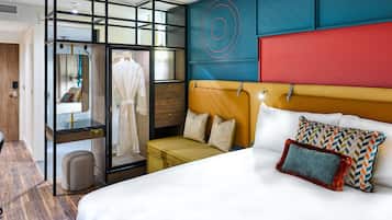 Una habitación de hotel con una cama, una zona de estar, un armario y un espejo.