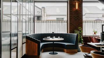 Un restaurante moderno con una zona de estar curva, una mesa redonda y un pilar de ladrillo.