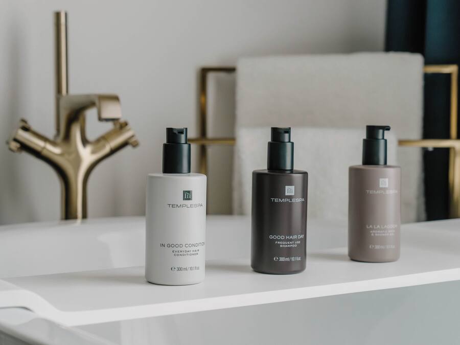 Tres productos de Temple Spa sobre un estante blanco.