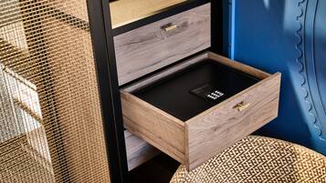 A wooden drawer with a black interior, a mesh screen, and a woven stool.