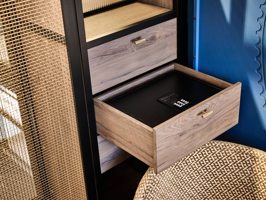 A wooden drawer with a black interior, a mesh screen, and a woven stool.