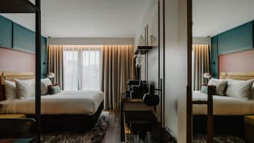 Une chambre d’hôtel avec deux lits, un bureau, une chaise, une machine à café et un miroir.