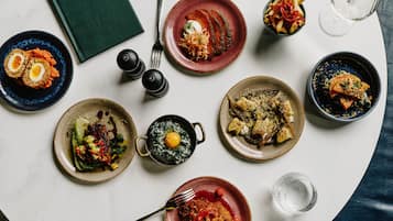A table with various dishes, a book titled 'Voyagers', salt and pepper shakers, and a wine glass.