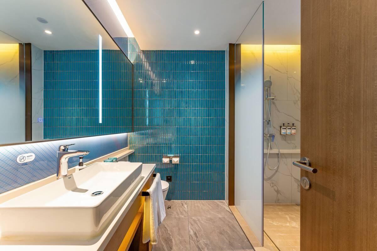 A modern bathroom with a large mirror, a sink, and a shower area.