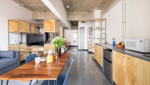 A modern kitchen with wooden cabinets, a dining table, and a built-in microwave. - Triver Florencia (Mexico City)