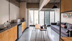 A modern kitchen with a built-in microwave, a dining area with a table and chairs, and a sofa in a living space. - Triver Florencia (Mexico City)