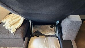 A sofa with a hidden storage compartment underneath, containing a mattress and pillows. - Quiet Stay in Elephant Butte Near Lake & Golf Course (Truth or Consequences)