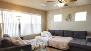 A living room with a sofa, a bed, a coffee table with a plant, and a ceiling fan. - Quiet Stay in Elephant Butte Near Lake & Golf Course (Truth or Consequences)