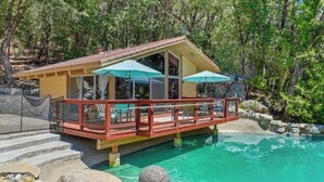 Eine Holzterrasse mit Pool, umgeben von Bäumen.