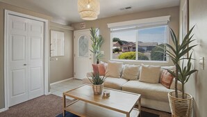 A living room with a sofa, a coffee table, a potted plant, and a hanging light fixture. - Zion Desert "Cruise" House - private pool, hot tub & game room (La Verkin)