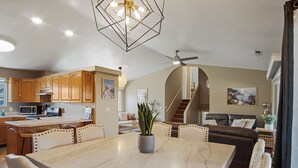 A spacious kitchen with wooden cabinets, a marble dining table, and a ceiling fan. - Zion Desert "Cruise" House - private pool, hot tub & game room (La Verkin)