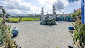 A courtyard with a fountain, potted plants, and a view of distant mountains. - OYO 92907 Miranda Hotel Syariah (Gresik)