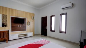 A spacious room with a large bed, a television mounted on the wall, and a window with a view. - OYO 92907 Miranda Hotel Syariah (Gresik)