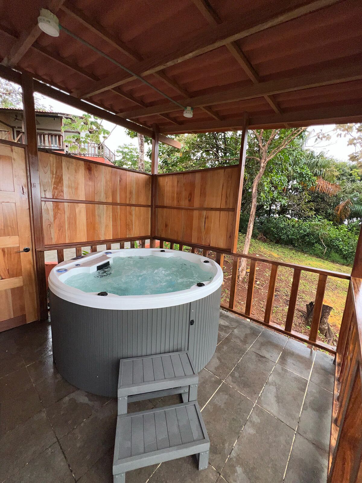 A wooden deck with a hot tub and a small step leading up to it.
