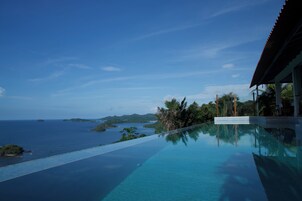 Vista deslumbrante de uma piscina infinita, com o mar e ilhas ao longe.
