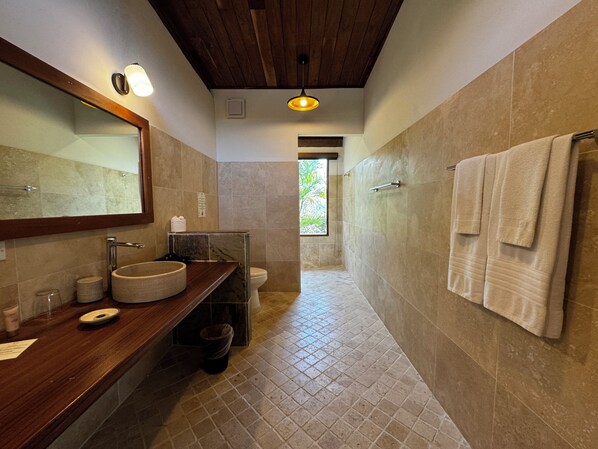 A bathroom with a wooden vanity, a large mirror, a round sink, and a towel rack. - Ciel y Miel  (Cacique)
