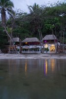 Uma propriedade à beira-mar com construções de palha, uma praia arenosa e águas calmas.