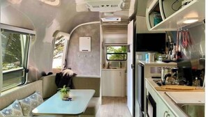 Un intérieur de camping-car compact comprenant un coin cuisine, un petit espace repas et un coin salon.