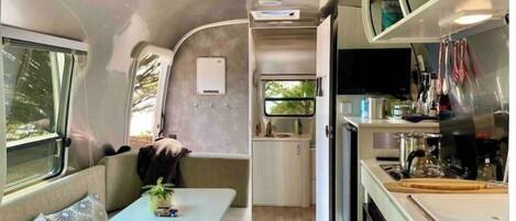 A compact RV interior with a kitchenette, a small dining area, and a seating space.