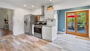 Una cocina con armarios blancos, un refrigerador de acero inoxidable y un horno empotrado.