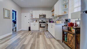 A modern kitchen with white cabinets, stainless steel appliances, and a wooden cabinet with a vintage design. - A Homey Haven Away from Home (Bristol)