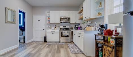 A modern kitchen with white cabinets, stainless steel appliances, and a wooden cabinet with a vintage design.