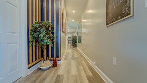 A hallway with wooden flooring, a potted plant, and a framed artwork on the wall. - A Homey Haven Away from Home (Bristol)