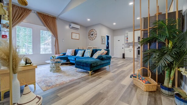 A modern living room with a blue sectional sofa, a coffee table, and a large window with curtains. - A Homey Haven Away from Home (Bristol)
