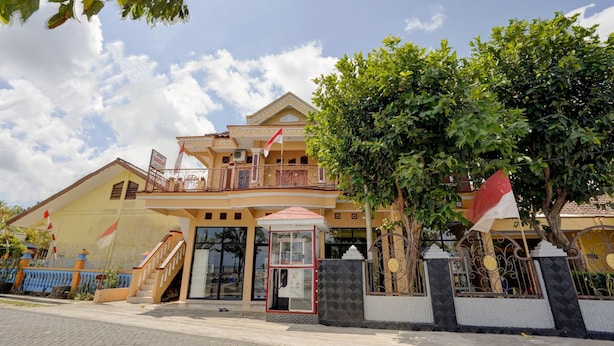Un bâtiment à deux étages doté d’un balcon, d’un petit kiosque d’entrée et d’un drapeau.