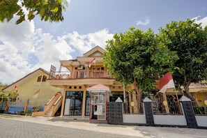 Un bâtiment à deux étages doté d’un balcon, d’un petit kiosque d’entrée et d’un drapeau.