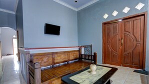 Une pièce comprenant un banc en bois, une table en marbre, une porte en bois et un téléviseur fixé au mur.