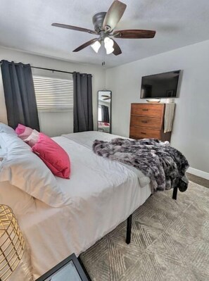 Cozy retreat with a large bed, flat-screen TV, and dresser.