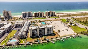A coastal hotel with multiple buildings, a marina, and a beach.