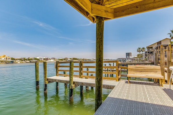 A wooden pier extending into calm water, with a bench and a covered area.
