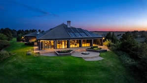 A modern house with a large glass facade, solar panels on the roof, and a well-maintained lawn. - Valley View Villa - Event Venue/Pheasant Hunting/Sleeps 18/9 Beds/6.5 Bath (Mitchell)