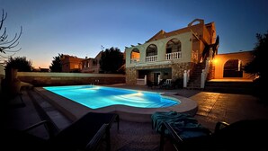 A swimming pool with a stone deck, a covered patio area, and a two-story house with a balcony. - Luxe 6P Kindervriendelijke Villa met Zwembad, Airco, Internet Wifi, Alarm en BBQ (Mazarrón)