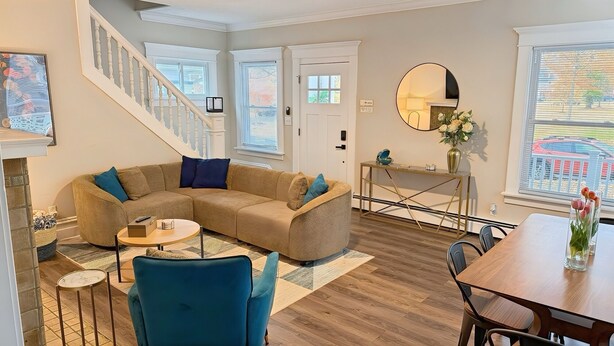 A living room with a sectional sofa, a coffee table, and a dining area with a table and chairs.