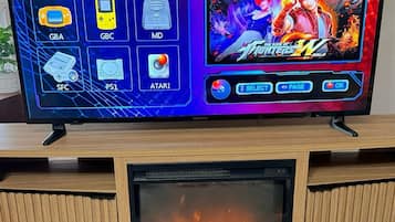 Un téléviseur diffusant un jeu vidéo, une cheminée et deux manettes posées sur une table.