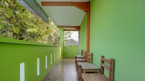Un corredor cubierto con paredes verdes y suelo de baldosas, que conduce a un espacio de descanso con bancos de madera.