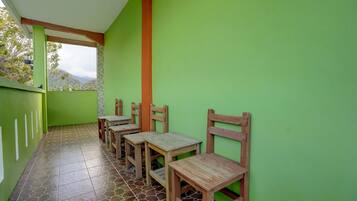 Un espace extérieur aménagé, abrité et doté de tables et de chaises en bois, de murs recouverts de verdure et d’un sol carrelé.