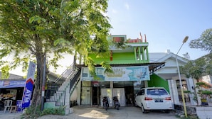 Una tienda de muebles con fachada verde y blanca, una escalera que lleva a la entrada y dos motocicletas estacionadas al frente.