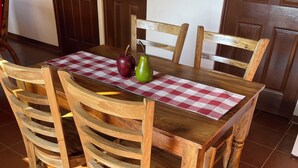Een houten eettafel met een geruit tafelkleed, omringd door houten stoelen met gebogen rugleuningen.