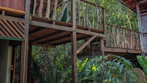 Une structure en bois dotée d’un balcon, entourée d’une végétation luxuriante.