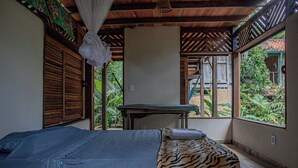Une chambre avec un lit, une moustiquaire et une vue sur l’extérieur.