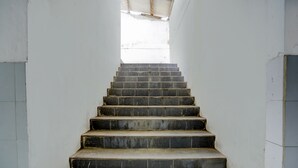 Una escalera con peldaños oscuros que ascienden, rodeada de paredes blancas.